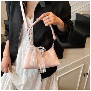 Détail du sac rose brillant avec poignée tressée, nœud en dentelle et perles nacrées