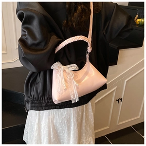 Détail du sac rose avec poignée tressée, nœud en dentelle et décor de perles