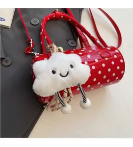 Close-up of red polka dot cylinder handbag with a cute white cloud plush charm detail