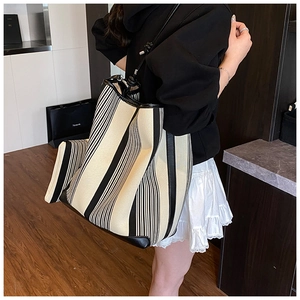 Detail view of large capacity striped tote bag with matching inner clutch shown on shoulder