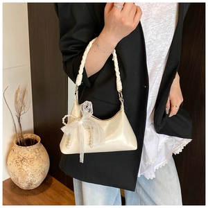 Gros plan du sac beige en cuir avec poignée tressée et noeud élégant en dentelle et perles
