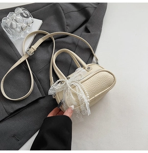 Detailed shot of cream pebbled leather bag with lace bow and pearl decoration