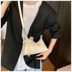 Détail du sac beige avec nœud en dentelle élégant et chaîne de perles décorative