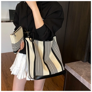 Striped canvas tote bag set with black leather trim shown in model street style