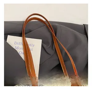 Close-up of woven tote bag showing brown leather handle and white stitching details