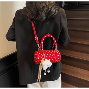 Red cylindrical polka dot bag with plush cloud charm shown on black blazer outfit