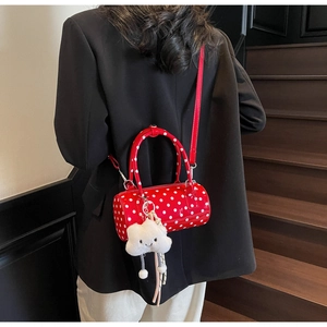 Close-up of red cylindrical polka dot bag featuring a plush cloud charm and strap