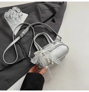 Detail of silver textured leather mini bag featuring lace bow and pearl pendant decor
