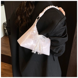 Gros plan du sac hobo rose avec poignée tressée et grand nœud en dentelle et perles