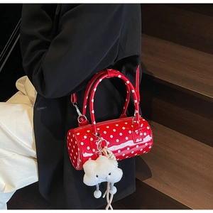 Detailed close-up of a red polka dot cylinder bag with a white plush cloud charm