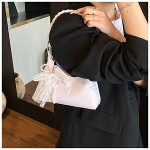 Détail du sac bandoulière avec nœuds en dentelle, perles et poignées tissées