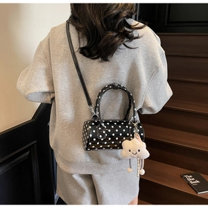 Close-up of black polka dot cylinder bag with white cloud plush charm detail