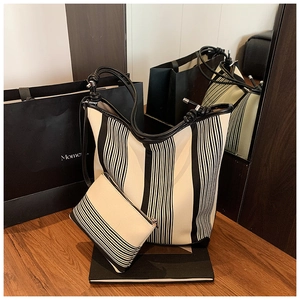 Detailed set of black and white striped tote bag with matching zippered pouch on wooden table