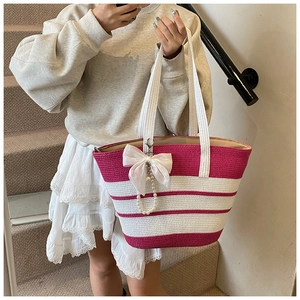 Detalle del bolso de paja a rayas rosas y blancas con un lazo blanco grande y perlas