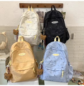Detalle de cuatro mochilas con patrón de mármol y colgantes de osito de peluche