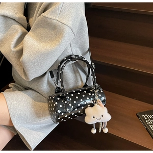 Close-up of black polka dot cylinder Boston bag with cute cloud charm and strap