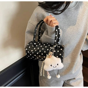 Polished black polka dot cylinder handbag with a plush cloud charm shown held by model