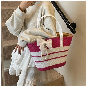 Dettaglio borsa tote in paglia a righe bianche e rosa con fiocco e catena di perle decor
