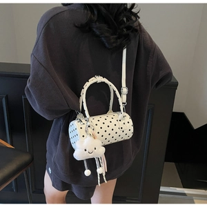 Back view of a model wearing a white polka dot cylindrical crossbody bag with cloud charm