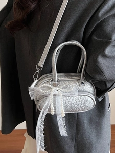 Silver bowling shoulder bag with pearl bow and lace charm worn with a grey blazer