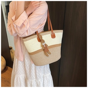 Detailed side view of a large woven straw bucket bag worn by a model in a cozy indoor setting