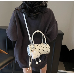 Polka dot cylindrical bag with white plush cloud charm shown in cross-body style