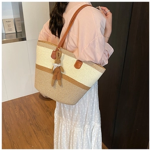 Detail of a large straw tote bag with dual-tone design and brown leather shoulder straps