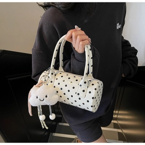 Close-up of a white cylindrical polka dot bag featuring a cute plush cloud charm