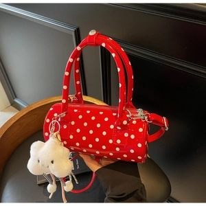 Close-up of red polka dot cylinder bag with glossy finish and cloud plush charm