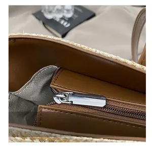 Detailed macro view of the smooth zipper closure and woven straw texture on the tote bag