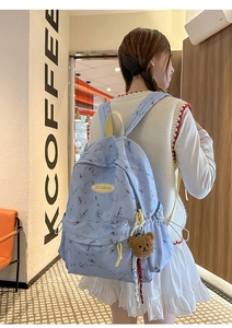 Detalle de la mochila azul claro con estampado de mármol, oso de peluche y logo RKDBAG