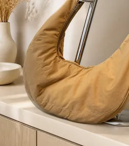 Detailed close-up of khaki nylon shoulder bag with white contrast stitching and soft folds