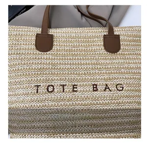 Detail of woven straw tote bag featuring contrast stitching and faux leather handles