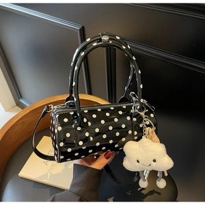 Detailed view of black polka dot cylinder bag with a white plush cloud charm accessory
