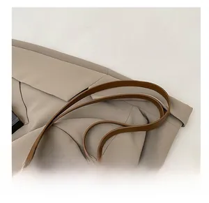 Close-up of durable brown faux leather shoulder strap with neat stitching on straw tote