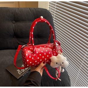 Detailed view of a red polka dot cylindrical handbag with a white cloud plush charm