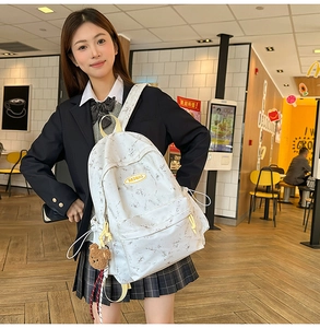 Detalle de la mochila con estampado de mármol blanco, cremalleras amarillas y oso de peluche