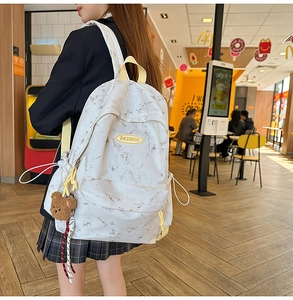 Mochila escolar con estampado de mármol y colgante de oso en escena de estilo