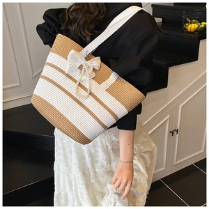 Detalle del bolso de paja a rayas con lazo de satén blanco y perla elegante