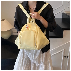 Detail of glossy pale yellow backpack with cartoon rabbit charm and zip pocket