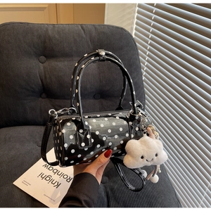 Close-up of black polka dot cylinder bag with cute cloud charm and metal buckles