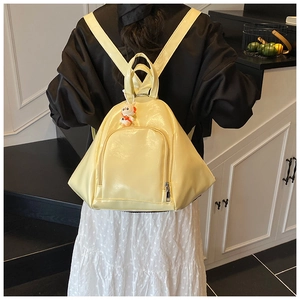 Detail view of yellow glossy backpack with cute rabbit charm on a minimalist model