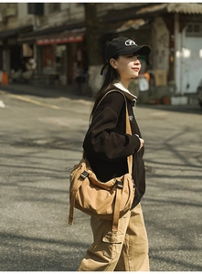 Outdoor-Aufnahme einer khakifarbenen Messenger-Bag mit verstellbarem Riemen im Streetstyle