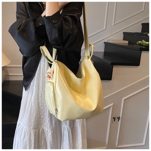Detail of bright yellow glossy tote bag with charms shown in a lifestyle stair setting