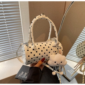 Close-up of a white cylindrical polka dot handbag with a soft cloud-shaped plush charm