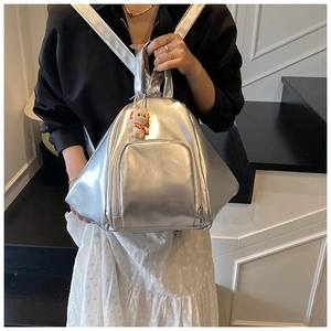 Detail of silver metallic geometric backpack with a cute white charm on the front pocket