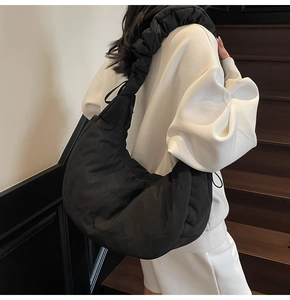 Close-up of black ruched shoulder bag showing moon shape and soft nylon texture