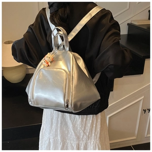 Detail of silver metallic triangle backpack with cute cat charm on minimalist background