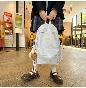 Detalle de mochila con patrón de mármol blanco con bolsillo lateral y colgante de oso