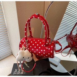 Close-up of red polka dot cylinder bag in glossy patent leather with plush cloud charm